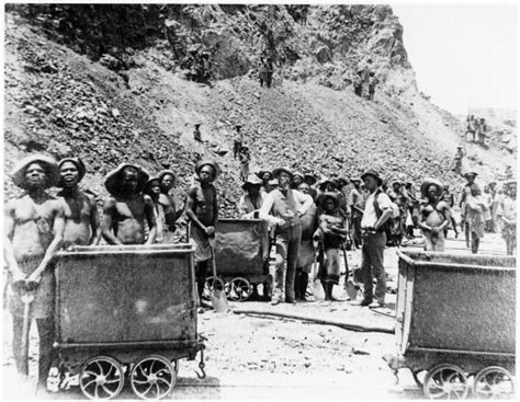 an old black and white photo of people standing in the dirt with carts behind them