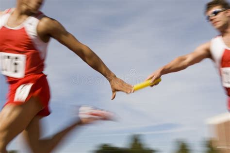 Runners Passing Baton In Relay Race Stock Image - Image: 29655361