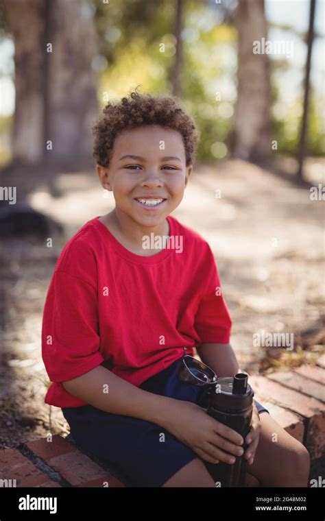 Portrait of smiling boy relaxing after workout during obstacle course Stock Photo - Alamy