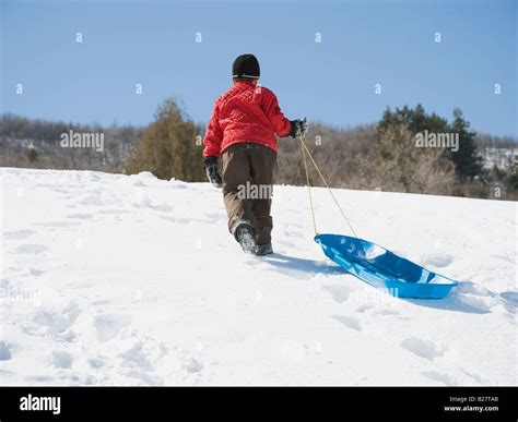 Boy pulling sled in snow Stock Photo - Alamy