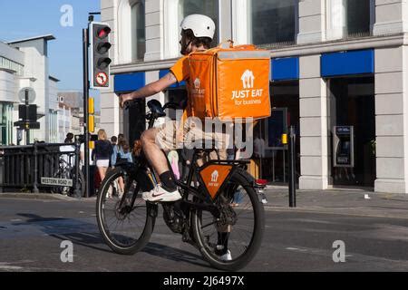 Just Eat courier delivery rider in orange uniform and Just Eat Scooter ...