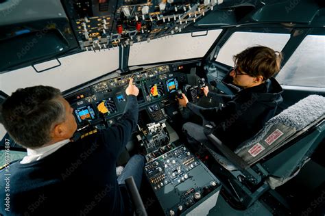 An experienced pilot instructs a young student before a training flight in the cockpit of an ...