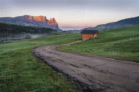 Alpe di Siusi or Seiser Alm, mountain path and Sciliar or Schlern mountain in sunrise light ...