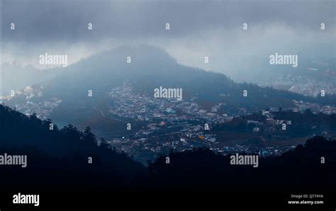 A beautiful shot of Ooty village view from Doddabetta peak under a cloudy sky in Tamil Nadu ...