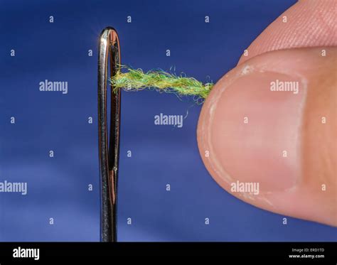 Threading.needle Closeup of a man's fingers threading through the eye ...