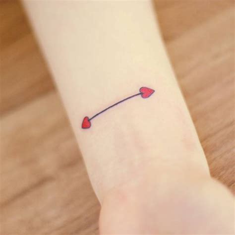 Double headed arrow tattoo on the left wrist, with