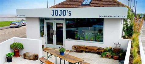 the outside of jojo's restaurant with benches and tables