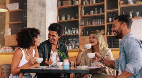 Young people sitting at a coffee shop and talking. Group of friends having coffee together in a ...