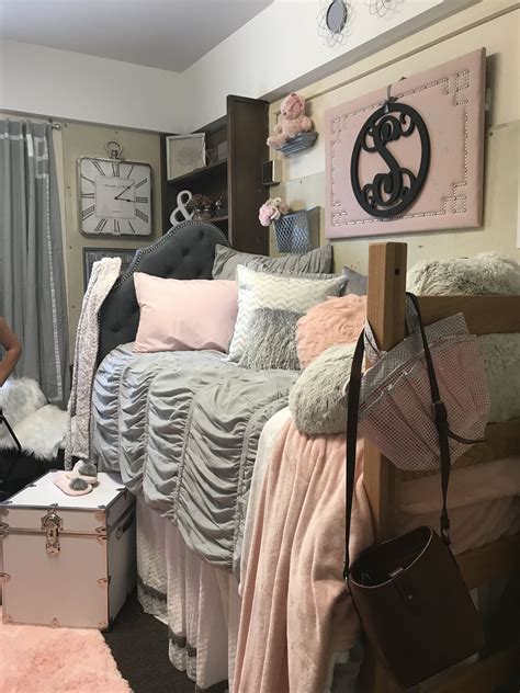 a woman standing in front of a bed covered in pink and grey sheets ...