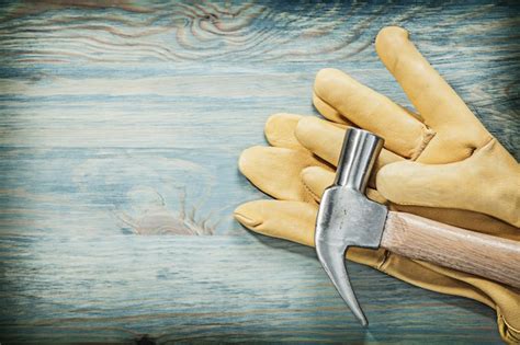 Premium Photo | Claw hammer safety gloves on wooden board construction concept