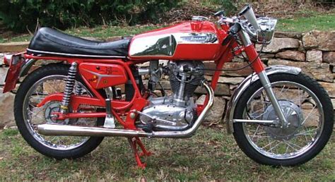 a red motorcycle parked next to a stone wall