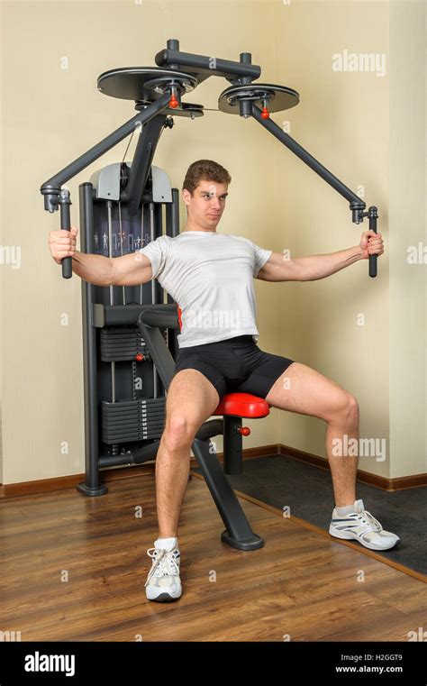 young man does workout at chest fly machine in gym Stock Photo - Alamy