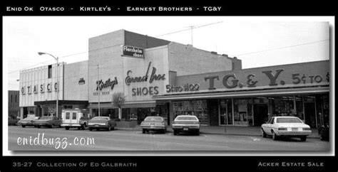 an old black and white photo of cars parked in front of shops