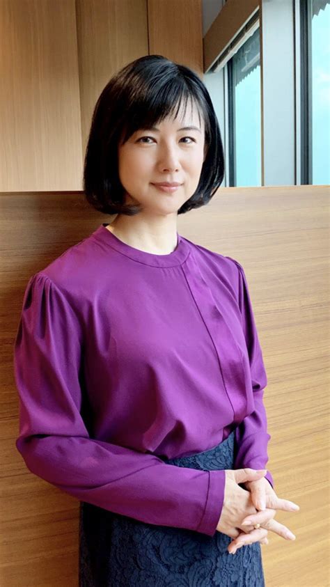 a woman standing in front of a wooden wall wearing a purple shirt and ...