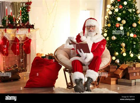 Santa Claus reading book in room decorated for Christmas Stock Photo - Alamy