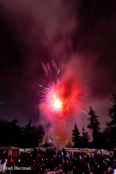 fireworks are lit up in the night sky above a large group of people at an outdoor event