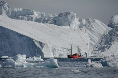 A tour boat among huge icebergs at the Ilulissat ice fjord in Greenland ...