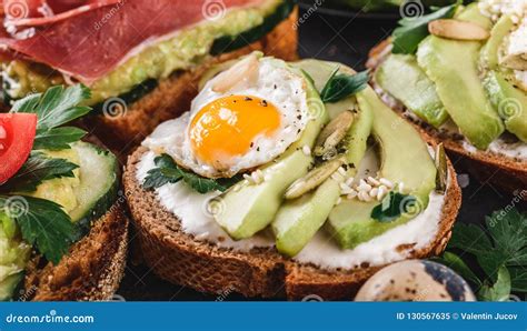 Whole Grain Bread Sandwiches with Fried Quail Egg, Avocado, Herbs and Seeds on Black Background ...