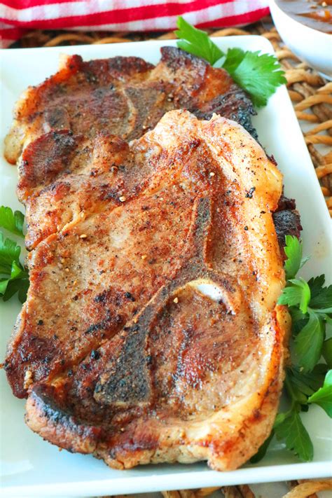 two pieces of meat sitting on top of a white plate next to some parsley