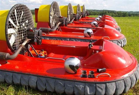 a row of red and yellow hovers sitting on top of a lush green field