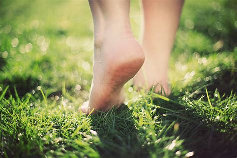 Walking barefoot across the grass. by Kitty Kleyn - Stocksy United