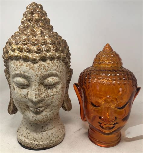 Lot - Two Buddha head sculptures: one amber colored glass and the other glazed ceramic.