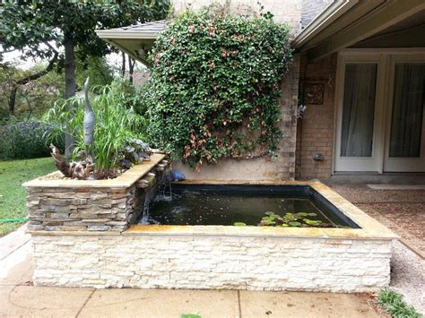 Side view of an modern, above ground koi pond with stacked rock & bog waterfall. This water ...