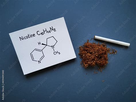 Structural chemical formula of nicotine molecule with tobacco dry heap and handmade cigarette ...