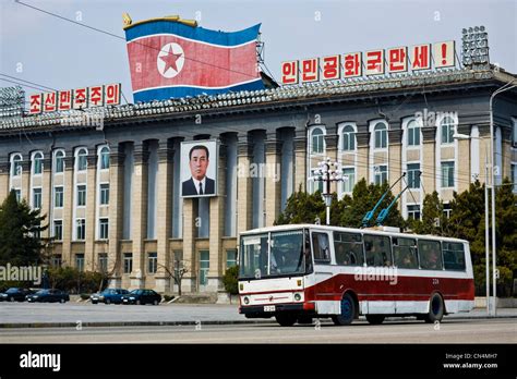 North Korea, Pyongyang, Kim Il-Sung square, trolley bus driving past a portrait of Kim Il-Sung ...