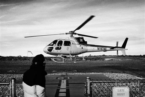 crew member watches papillon helicopter tour land on helipad at Grand canyon west airport ...