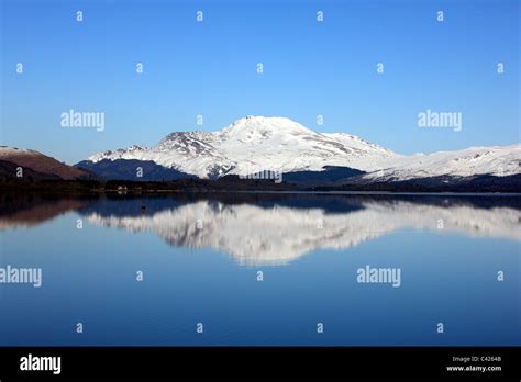 Ben Lomond with winter snow reflected in a very calm Loch Lomond Stock ...