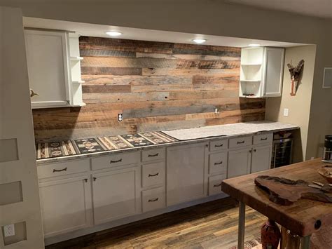 a large kitchen with white cabinets and wood wall covering the backsplash, along with an island ...