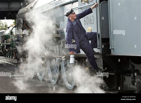 A steam engine driver climbs into his cab. The train is 60163 Tornado ...