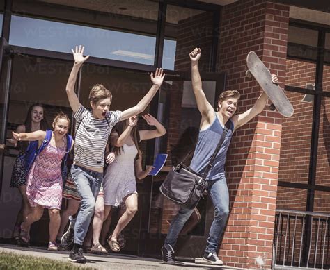 Male and female high school students running out of high school stock photo