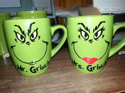 two green mugs with faces drawn on them sitting on a table next to each ...