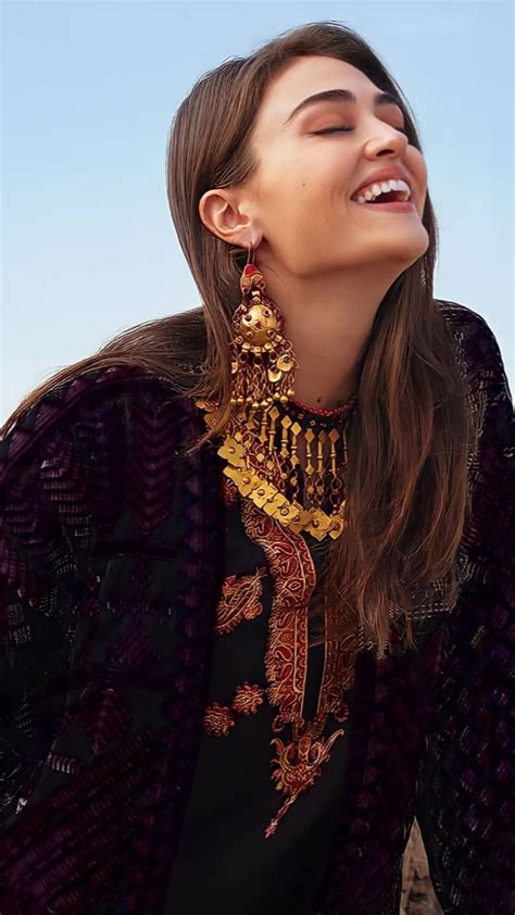 a woman with her eyes closed wearing an ornate necklace and earrings ...