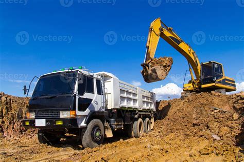 Backhoe digging and trucks. 7416369 Stock Photo at Vecteezy