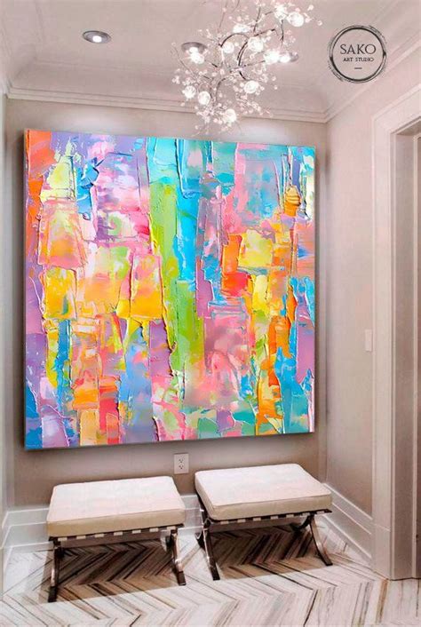 an abstract painting hangs on the wall above two stools in front of a ...