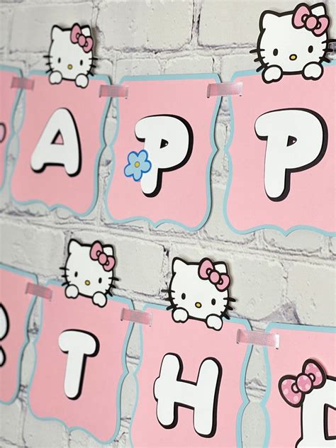 hello kitty birthday banner hanging on a brick wall with pink and white ...