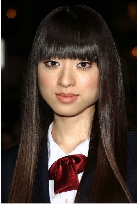 a woman with long black hair wearing a red bow tie