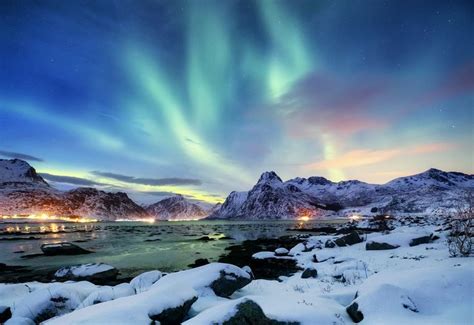 an aurora bore over the mountains at night with snow on rocks and ...