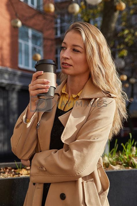 caucasian attractive woman in beige trench coat holding cup of coffee ...