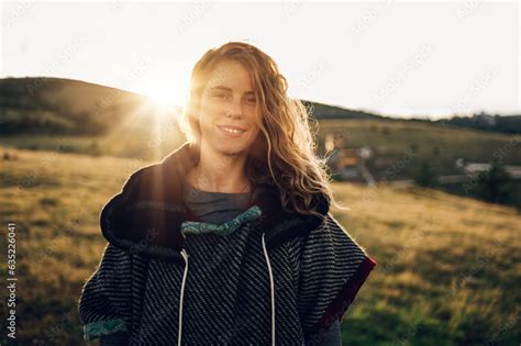 Portrait of a stylish woman hiking on a mountain path with tall grass ...