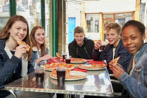 Group of teenagers eating pizza in cafe - Stock Photo - Dissolve