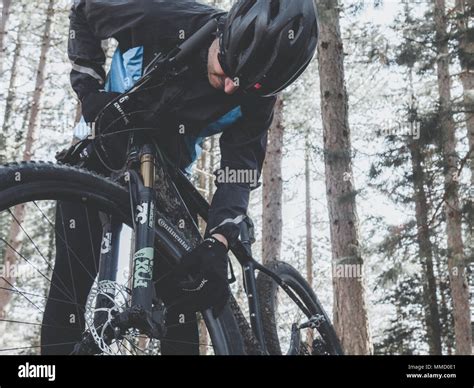 a cyclist near his mountain bike, fixs his bike, black out fit Stock Photo - Alamy