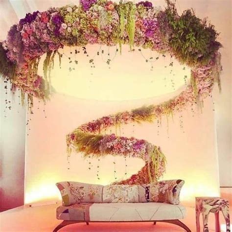 a couch sitting in front of a white wall with flowers on it and lights behind it