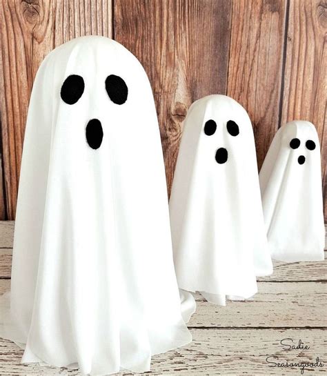 three white ghost statues sitting next to each other on a wooden floor with wood planks in the ...