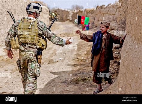 A young boy waves an Afghan flag along a village road as a US soldier patrols March 12, 2013 in ...