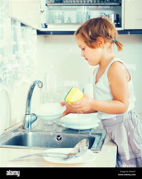 Serious little child washing dishes at domestic kitchen Stock Photo - Alamy