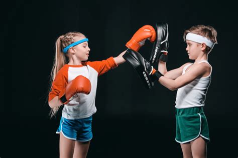 Seitenansicht von Kindern, die vorgeben, isoliert auf schwarzem, aktivem Kinderkonzept zu boxen ...